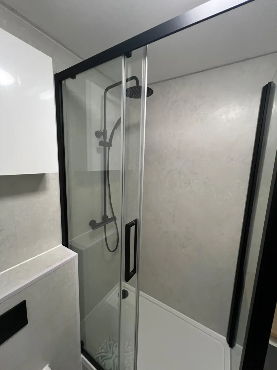 Black-framed shower with patterned flooring and white fittings